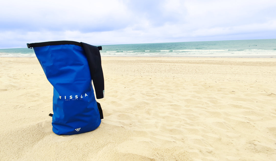 Blue Vissla dry bag placed on beach