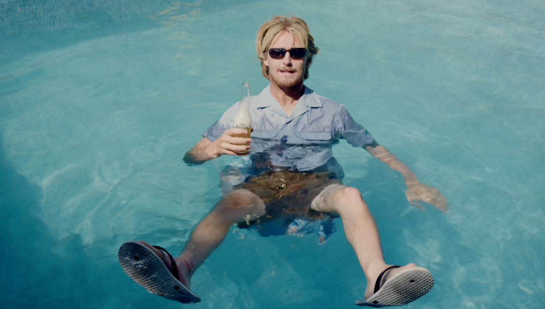 Josiah Amico fully clothed sitting in water with a beer