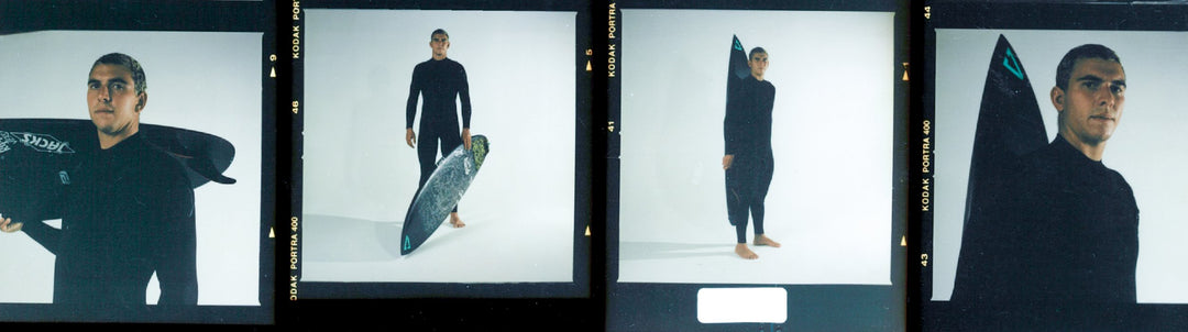 Surfer Cole Houshmand in a black Vissla High Seas wetsuit holding his surfboard