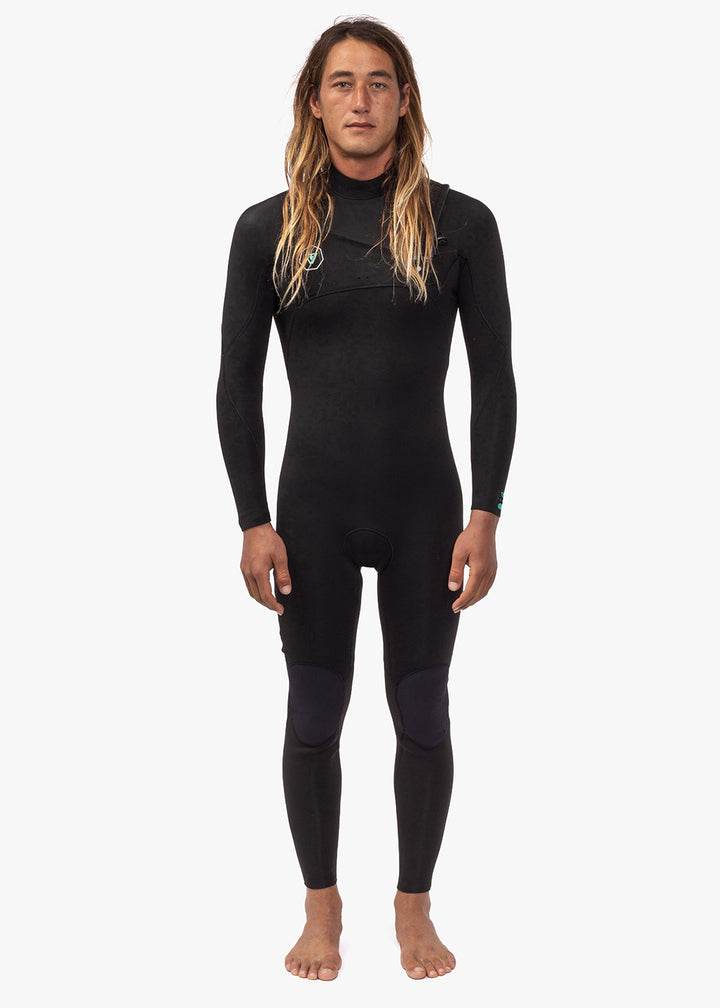A person wearing a full-body black surfing wetsuit, standing against a white background.